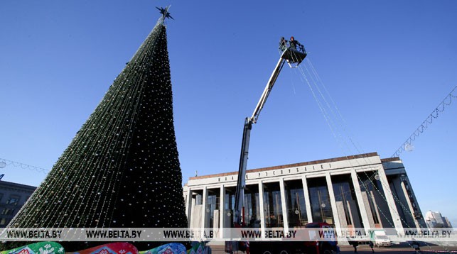 На фото специалисты УП "Мингорсвет" завершают украшение елки новогодней иллюминацией