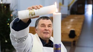 Ксендз Генрих Акалатович зажигает свечу от Вифлеемского огня мира