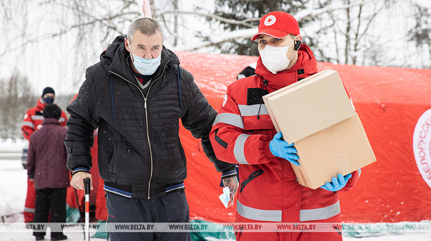Главный специалист Минской городской организации БОКК Артем Арешко помогает отнести продуктовый и гигиенический набор