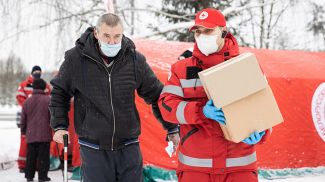 Главный специалист Минской городской организации БОКК Артем Арешко помогает отнести продуктовый и гигиенический набор