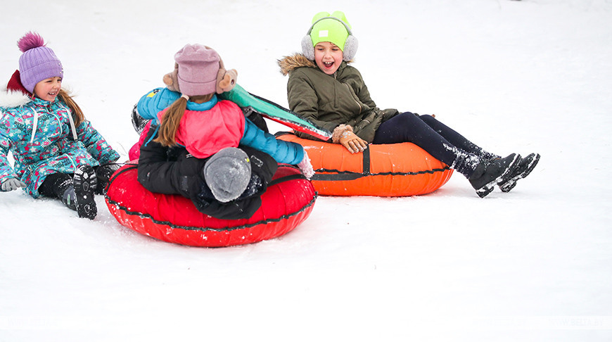 Зимние развлечения: дети катаются с горок на санках и тюбингах
