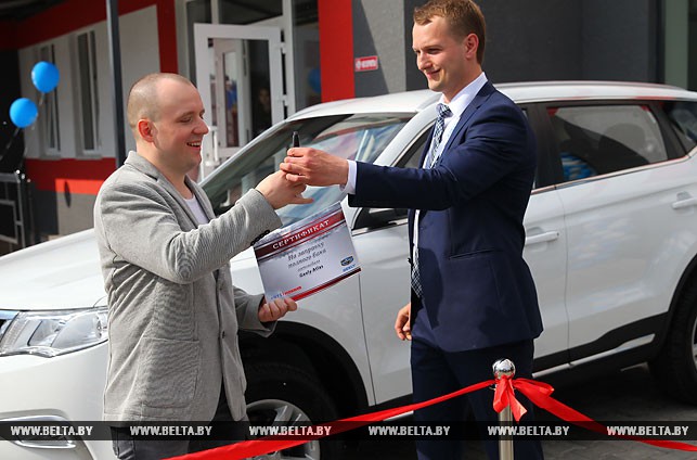 Первый покупатель дилерского центра Роман Годунов получает ключи и сертификат на топливо для своего нового Geely Atlas.