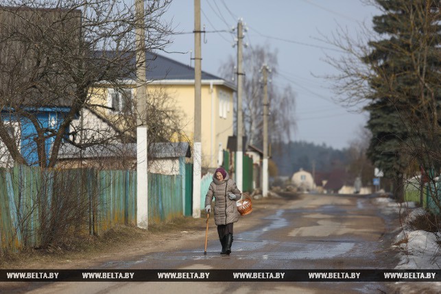 Женщина идет по сельской улице к костелу в Ракове, чтобы освятить пасхальную пищу