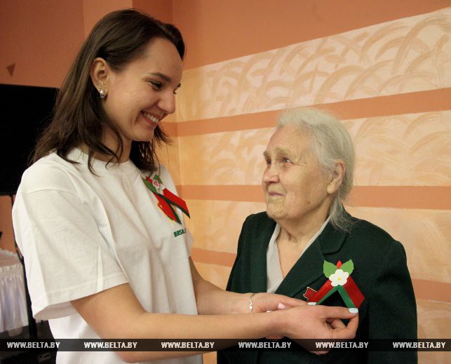 Член БРСМ Дарья Новикова прикрепляет бутоньерку Герою Социалистического труда Марие Анибраевой