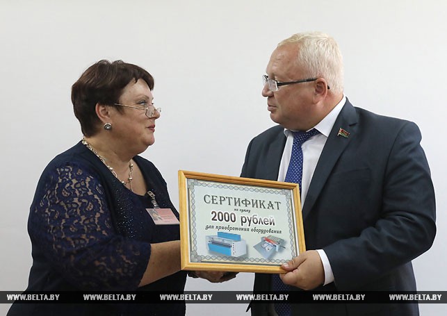 Председатель Витебского областного Совета депутатов Владимир Терентьев вручает сертификат директору центра социального обслуживания Наталье Ивановой.