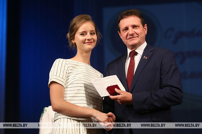 Председатель Гродненского городского Совета депутатов Борис Федоров вручает аттестат и медаль Ульяне Федосенко