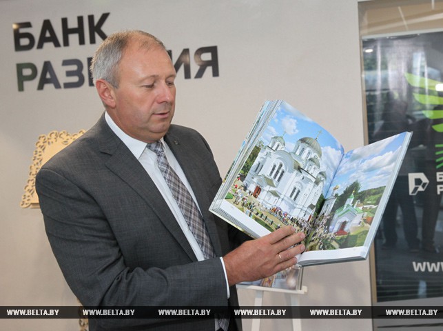 Председатель правления банка Сергей Румас показывает новую книгу-альбом "Симфония столетий"