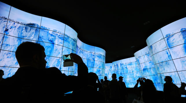 Люди входят в стенд LG Electronics через тоннель телевизоров OLED