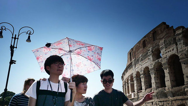 Туристы гуляют под зонтиками возле Колизея в Риме. Фото AFP