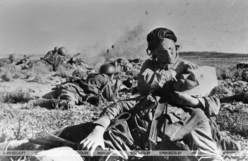Сестра милосердия оказывает помощь раненому на поле боя, декабрь 1943 года