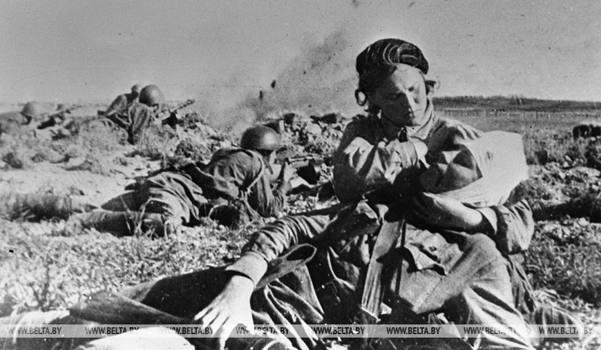 Сестра милосердия оказывает помощь раненому на поле боя, декабрь 1943 года