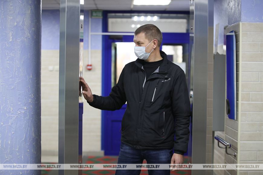 Посетитель городского клинического центра травматологии и ортопедии проходит через рамку для бесконтактной дезинфекции Посетитель городского клинического центра травматологии и ортопедии проходит через рамку для бесконтактной дезинфекции