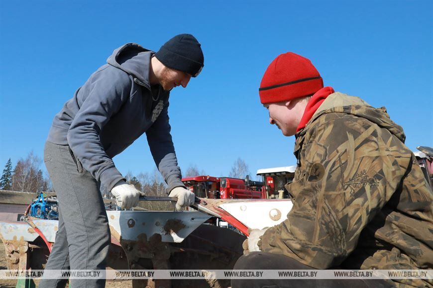 Механизатор Евгений Кошелев и студент Илья Савич во время проведения ремонтных работ